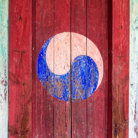 Eum and Yang Symbol, korean variant of Yin and Yang. Colorful retro painting with red background on a wooden door.の写真素材