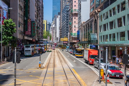 Street Scenario of a Hongkong central Boulevard Road with Tramway, Pedestrians and Cars between Skyscraper. In Yau Tsim Mong, Hong Kong, Chinaのeditorial素材
