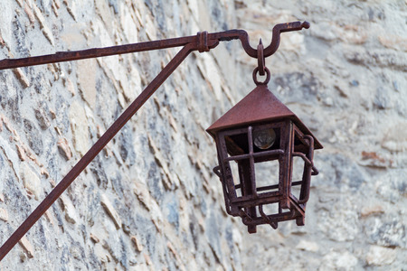 An antique iron street lamp hanging on the castle wall, a rusty metal street lampの写真素材