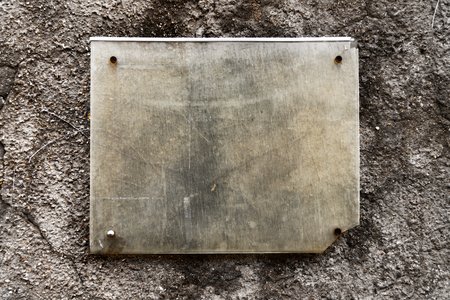 An old tablet hanging on a stone wall, a sign for placing text, a beautiful textureの写真素材