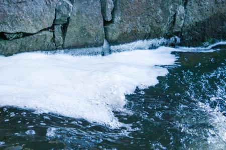 View of the water with white foam near large stones. Colorful background and water.の写真素材