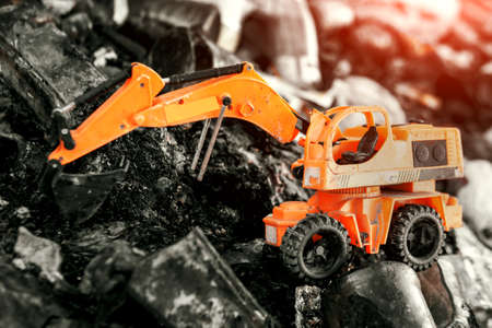 Orange toy excavator raking in a big pile of garbageの写真素材
