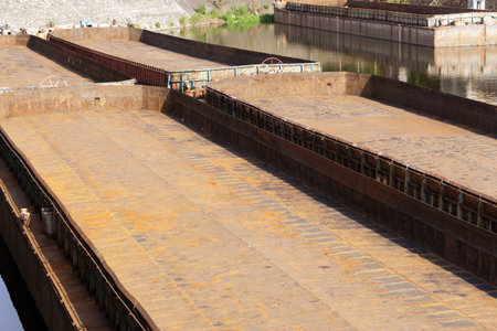 An old rusty barge moored in port after unloading coal at a power plant.