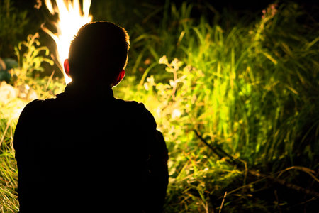 Rest near the fire in the evening. A young man sits by the fire. Camping. Bonfireの写真素材