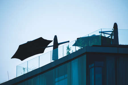 Umbrella on the roof of the house against the sunsetの写真素材