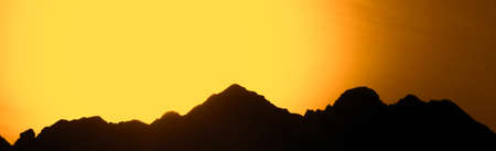 Big mountains on a background of orange sunset. Beautiful panorama of the mountainsの写真素材