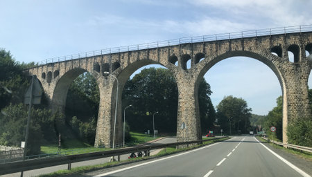 Old arched stone bridge over a road in Germanyの写真素材