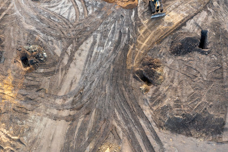 The excavator digs a trench under the foundation, and the bulldozer clears the ground. Top view of a...