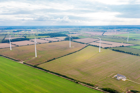 Green meadow with wind turbines generating electricity, summer landscape with blue sky, alternative...