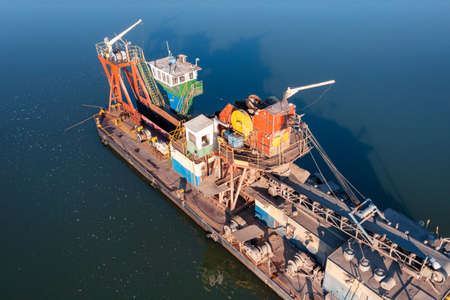 A floating platform with a huge bucket and conveyor belt extracts sand from the bottom of the ocean. Extraction of sand from the bottom of the ocean. Aerial photographyの写真素材