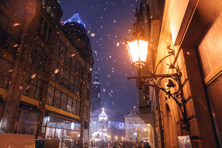 Christmas landscape on the street. A yellow street lamp between the houses illuminates the street and white snow falls. Wroclaw, Polandの写真素材