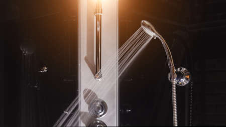 Water drops flowing from shower head in bathroom on black backgroundの写真素材