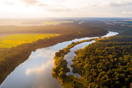 Summer landscape. A meandering river flows through trees and fieldsの写真素材