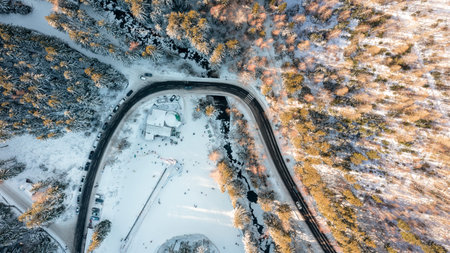 Winter landscape from the air, view of the mountain river and the road passing through the forest....