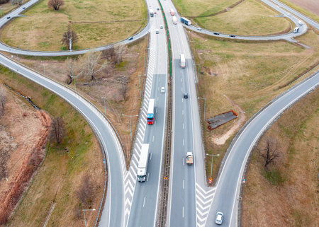 Aerial view of a motorway with interchanges, many trucks are driving on the road, transport...