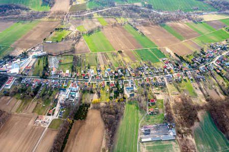 Aerial view of a small town among green fields, a small village, a long street and many private houses, landscapeの写真素材