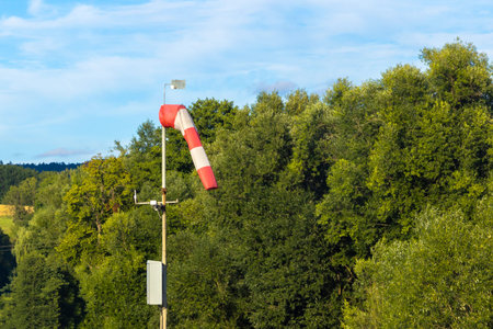 Wind direction flag near the airport against the background of trees