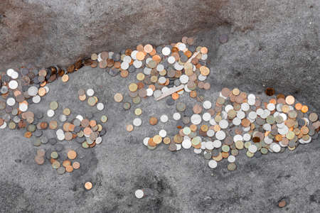 Many coins of different denominations lie on a stone, travelers leave coins to return somedayの写真素材