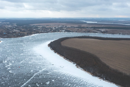 View from a height of a frozen river in winter, severe frosts, a beautiful river stretching into the distance, strewn with snowの写真素材
