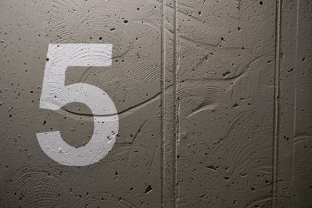The number 5 painted stencil on a concrete wall