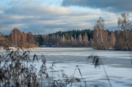 Russian winter landscape with trees and frozen pond on a sunny day.の写真素材