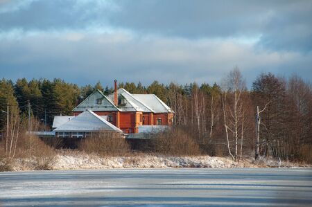 Russian winter landscape with a residential country house on the shore of a frozen pondの写真素材
