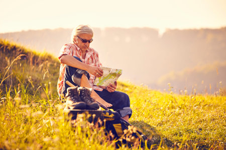 Man with map in meadow sittingの写真素材