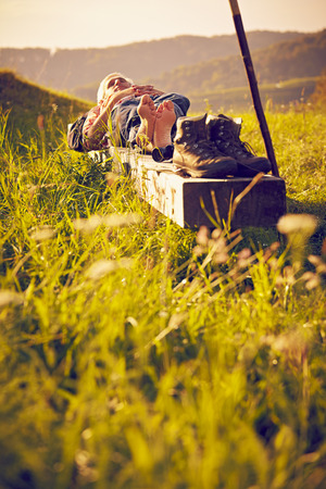 Man sleeping on bench in meadowの写真素材