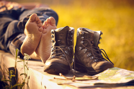 Shoes of a man lying on bench in the sunsetの写真素材