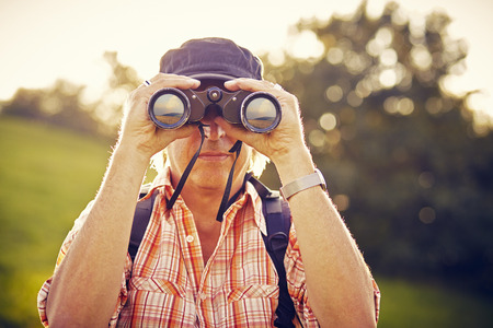 Man with hat and binoculars in natureの写真素材
