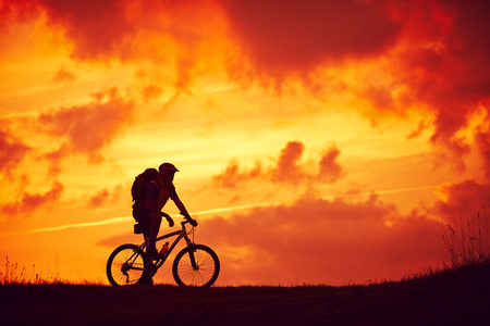 Man and mountain biking pleasure red cloudsの写真素材