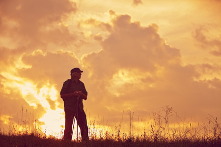 Hiker with cap and sticks on meadowの写真素材
