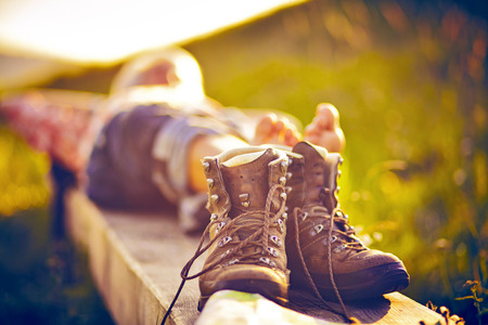 Man lying on bench and hiking boots standingの写真素材