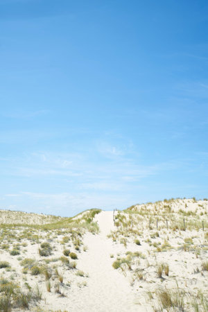 Dune with path and hill with sand and grass and sky without clouds