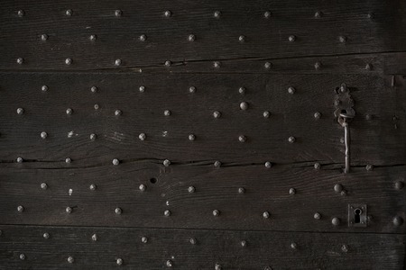 Wooden door old and dark wooden and metal studs with keyhole and door knockerの写真素材