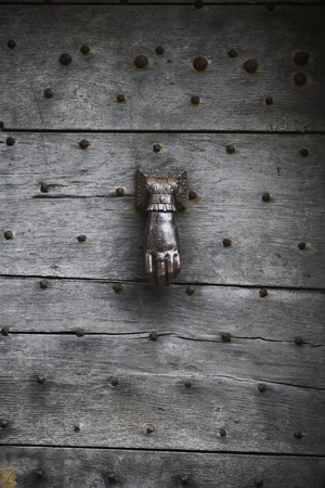 Wooden door old and dark wooden and metal rivets with door knocker as a hand