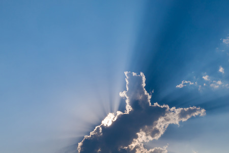 Animal shaped (dog) cloud in blue sky with sunbeamの写真素材