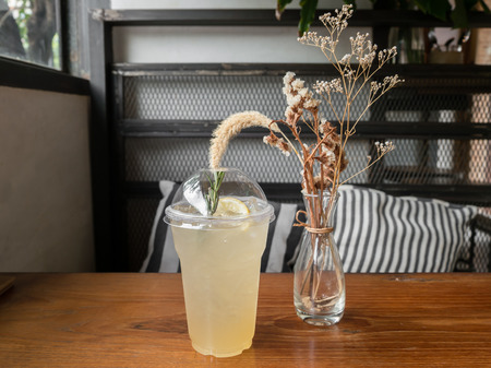 Lemonade in plastic cup on wooden table with cafe backgroundの写真素材