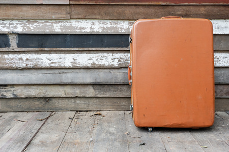 Old vintage brown suitcase on wooden wallの写真素材