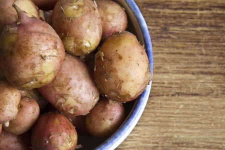 Bunch of raw potatoes with a wooden backgroundの写真素材