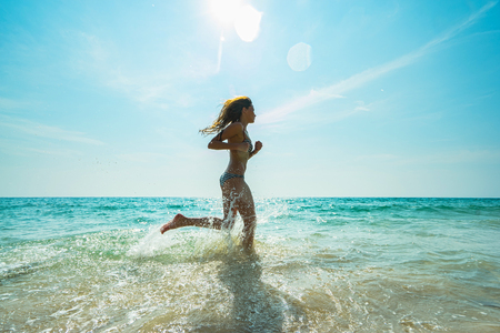 Young woman hight speed running in sea with splashesの写真素材