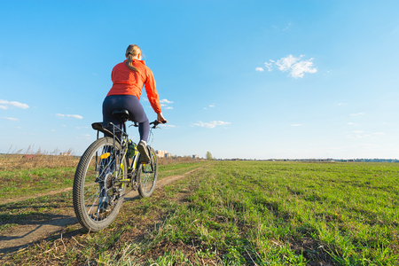 Bike riding - Young woman trying to ride on a bicycle in nature offroadの写真素材