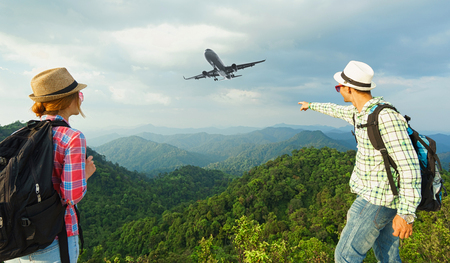 Hikers on the top of mountain looking on plane in the sky. Travel conceptの写真素材