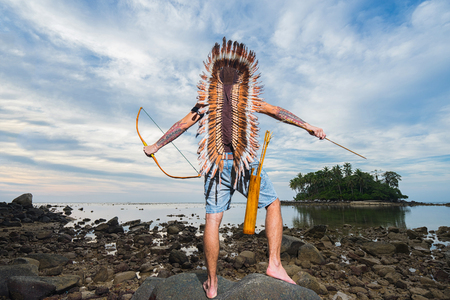 Indian man warrior with bow on the rocky shore. Back view.の写真素材