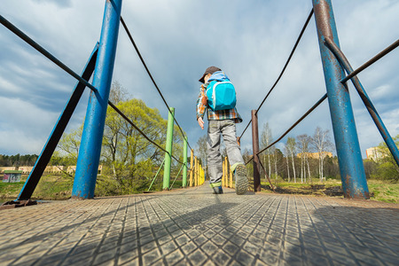 Small boy with backpack walking on the bridge.の写真素材