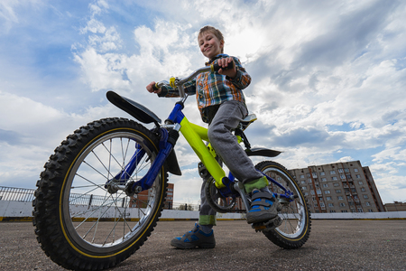 Urban biking - small happy  boy and bike in city. Focus on boyの写真素材
