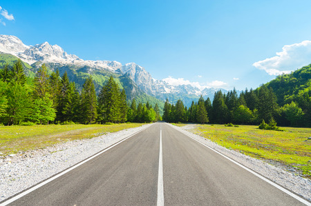 Road in forest to Mountain with snow-capped peaks.の写真素材