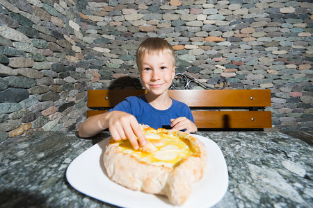 Boy eating hachapuri - traditional geargian food. Focus on child face.の写真素材