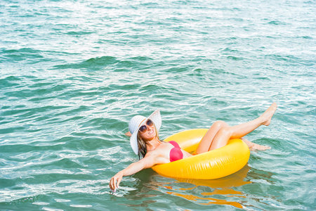 Happy woman in hat relaxing on the rubber ring on the sea.