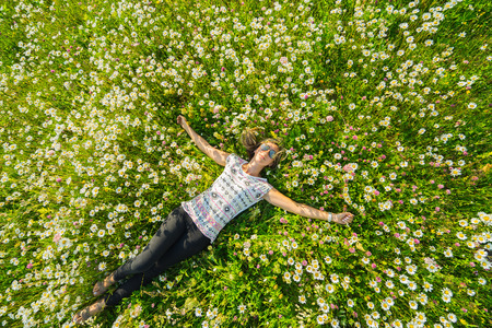 Young beautiful woman relaxing in the field with flowers. Overhead view.の写真素材
